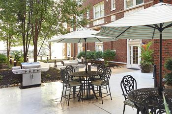 a patio with tables and chairs and umbrellas and a grill